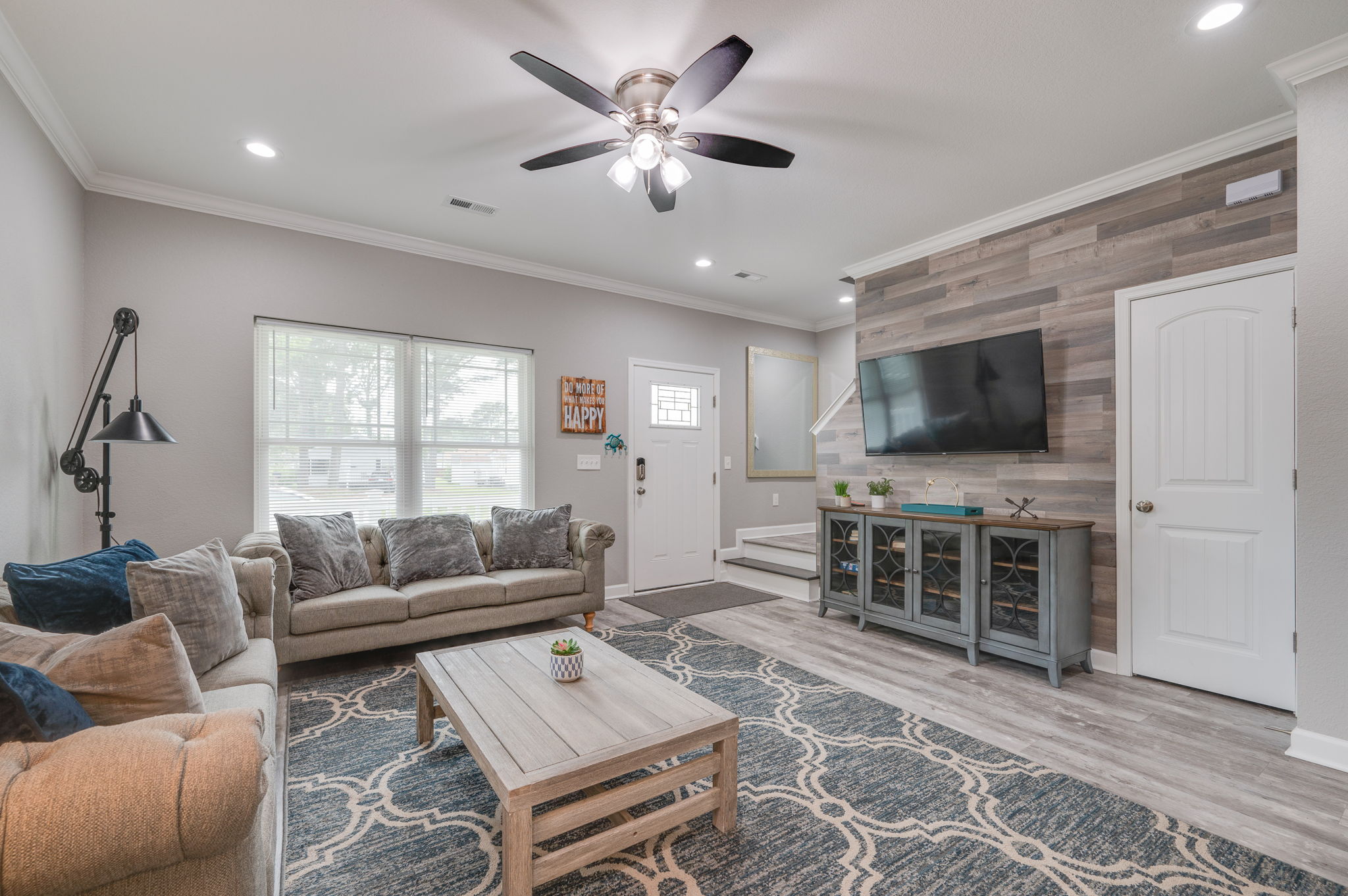 Living room entertainment center with wall-mounted TV and wood accent wall.