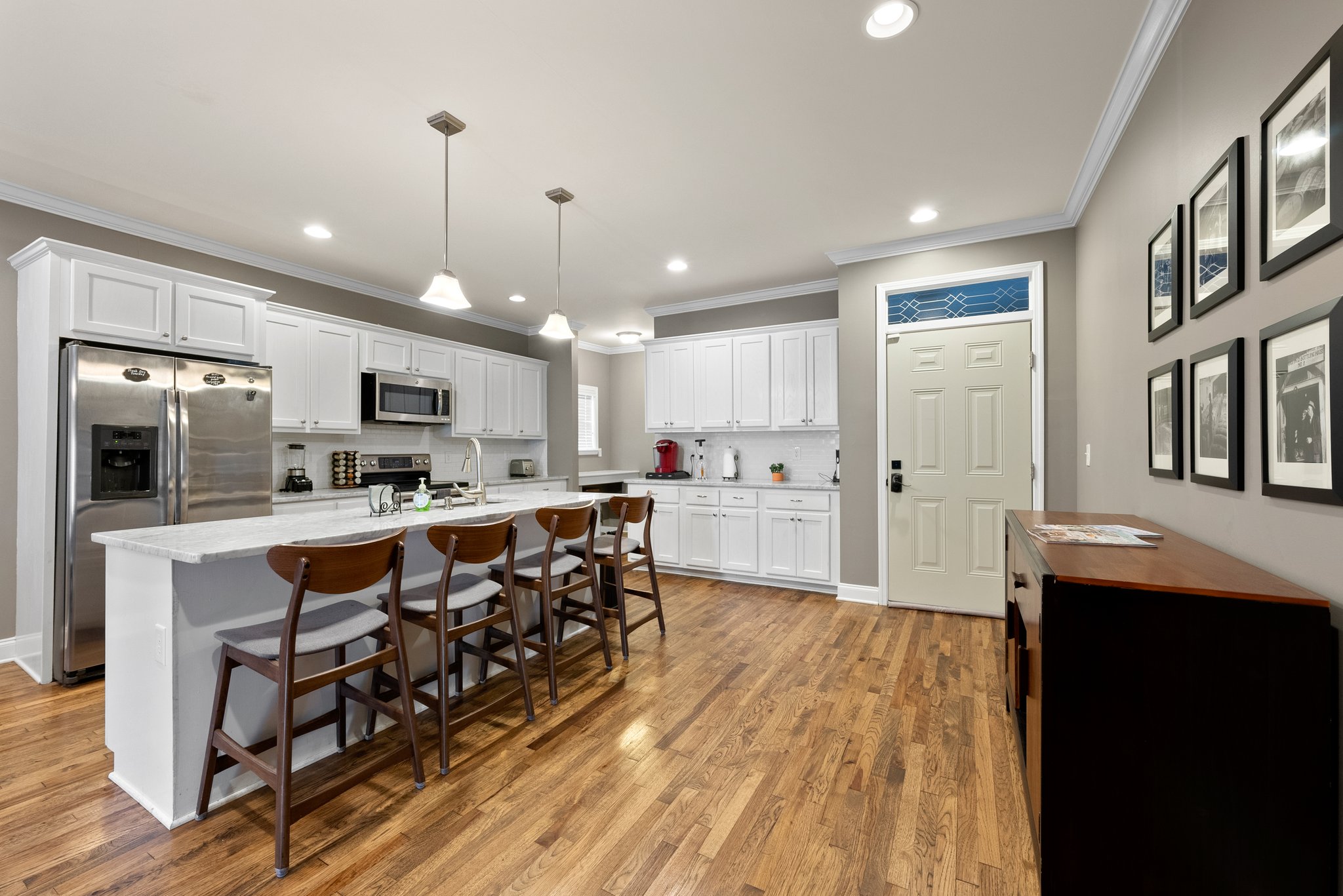 Modern kitchen with white cabinets, marble countertops, and bar seating