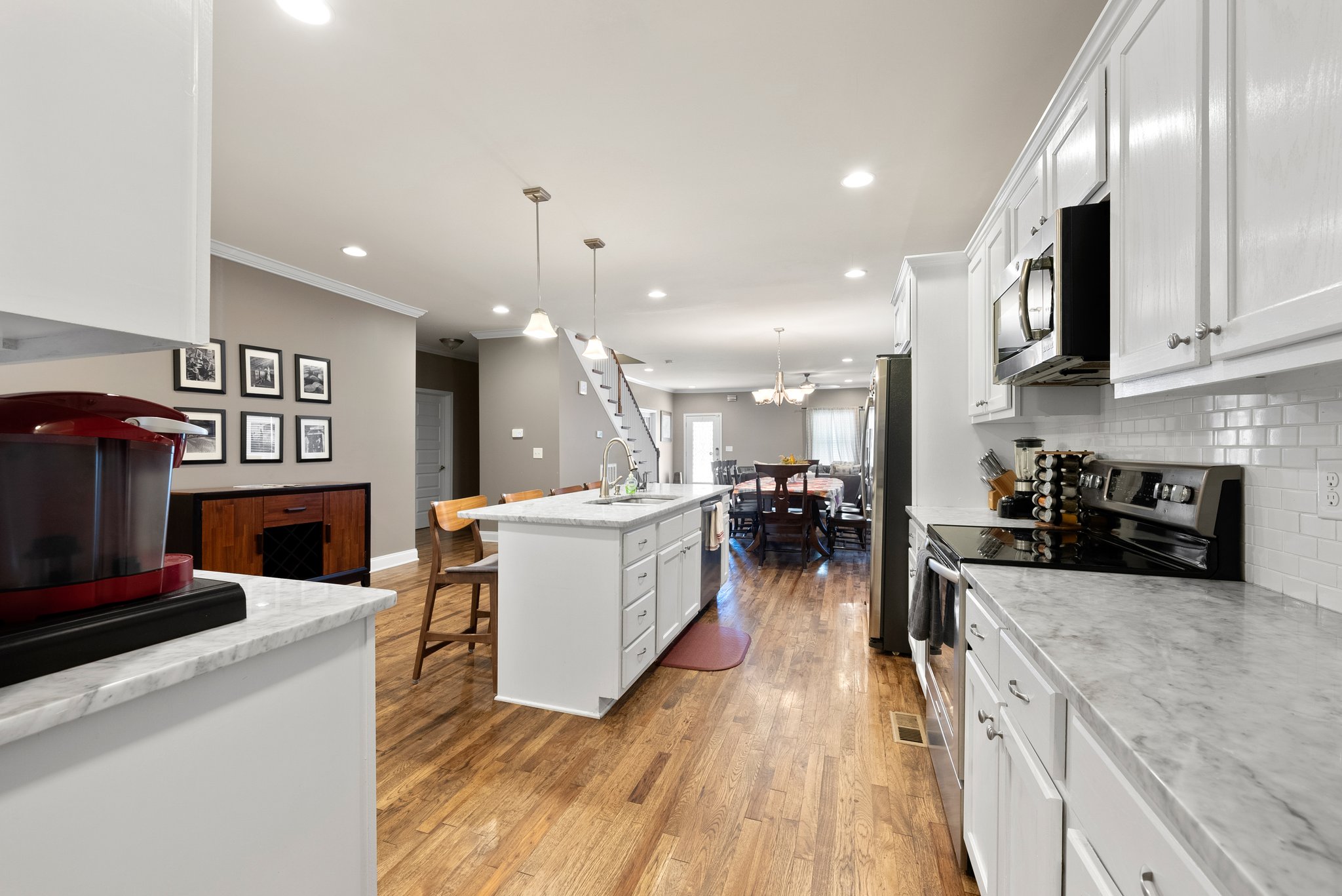 Open-concept kitchen and dining area with hardwood floors and modern lighting