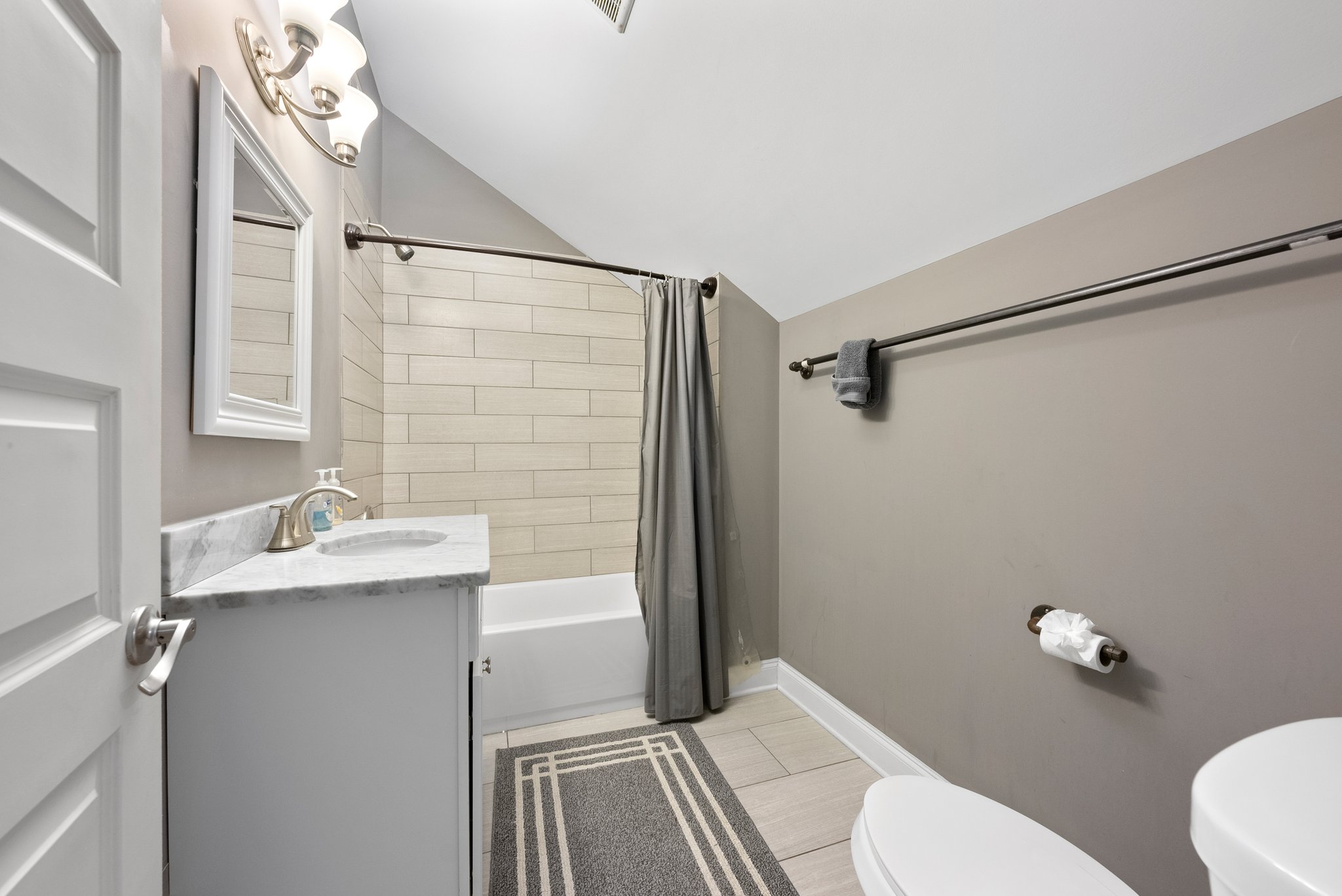 Modern bathroom with shower-tub combo and white vanity