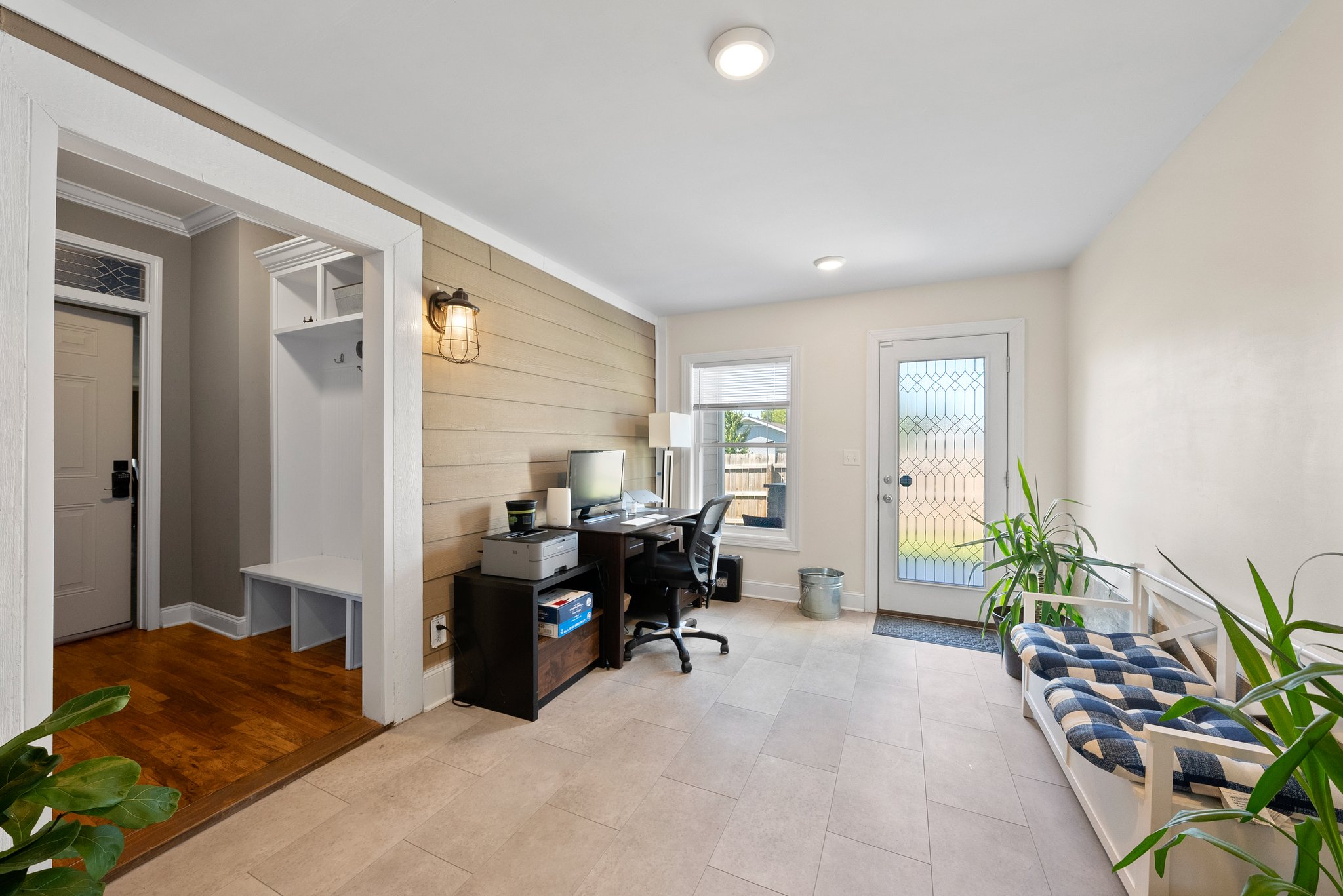 Home office with desk, chair, and plants in sunroom