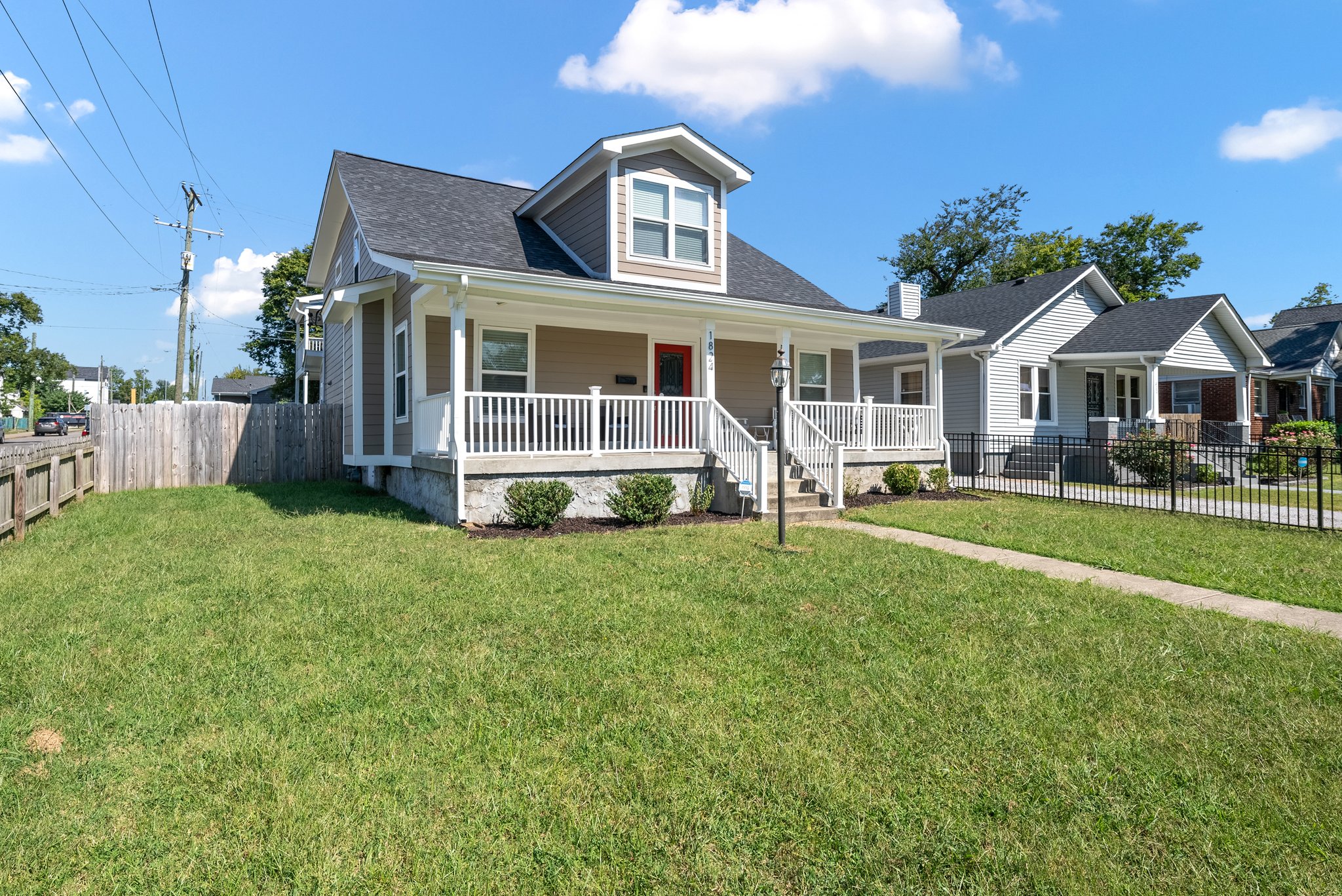 Side view of craftsman home with white railing and green lawn