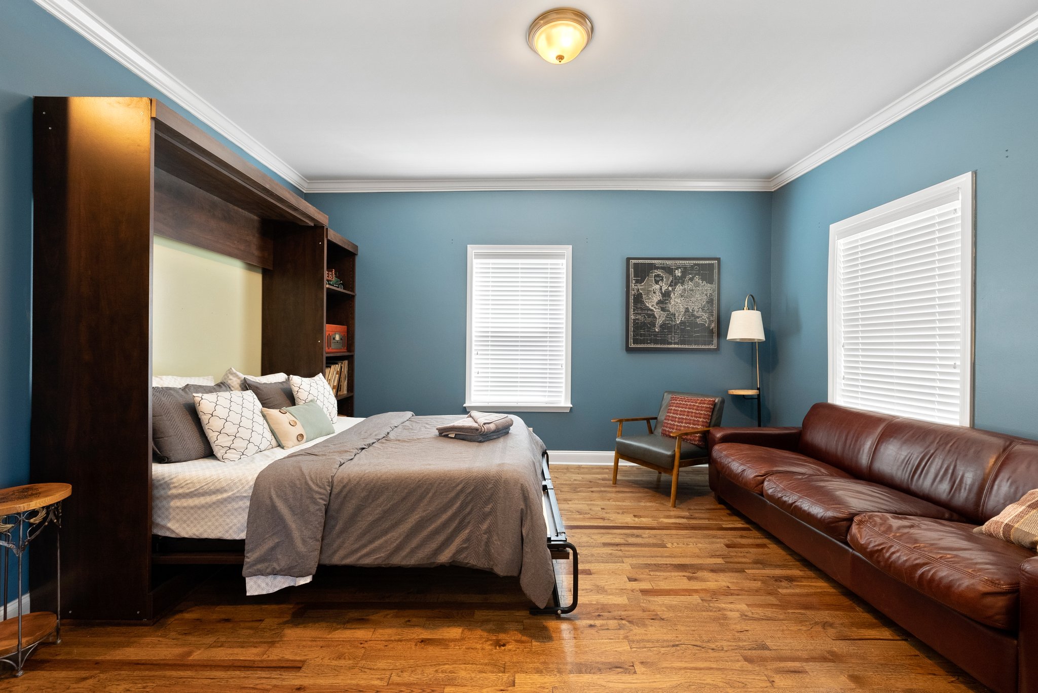 Spacious bedroom with murphy bed, leather sofa, and hardwood floors