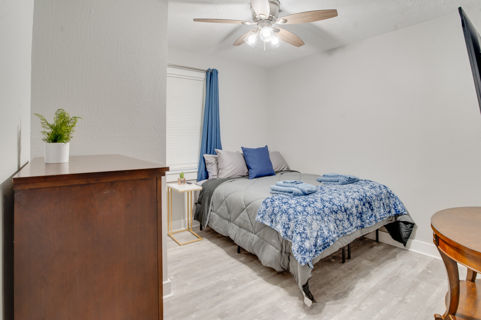 Bedroom with a red dresser, mounted TV, and neatly folded towels