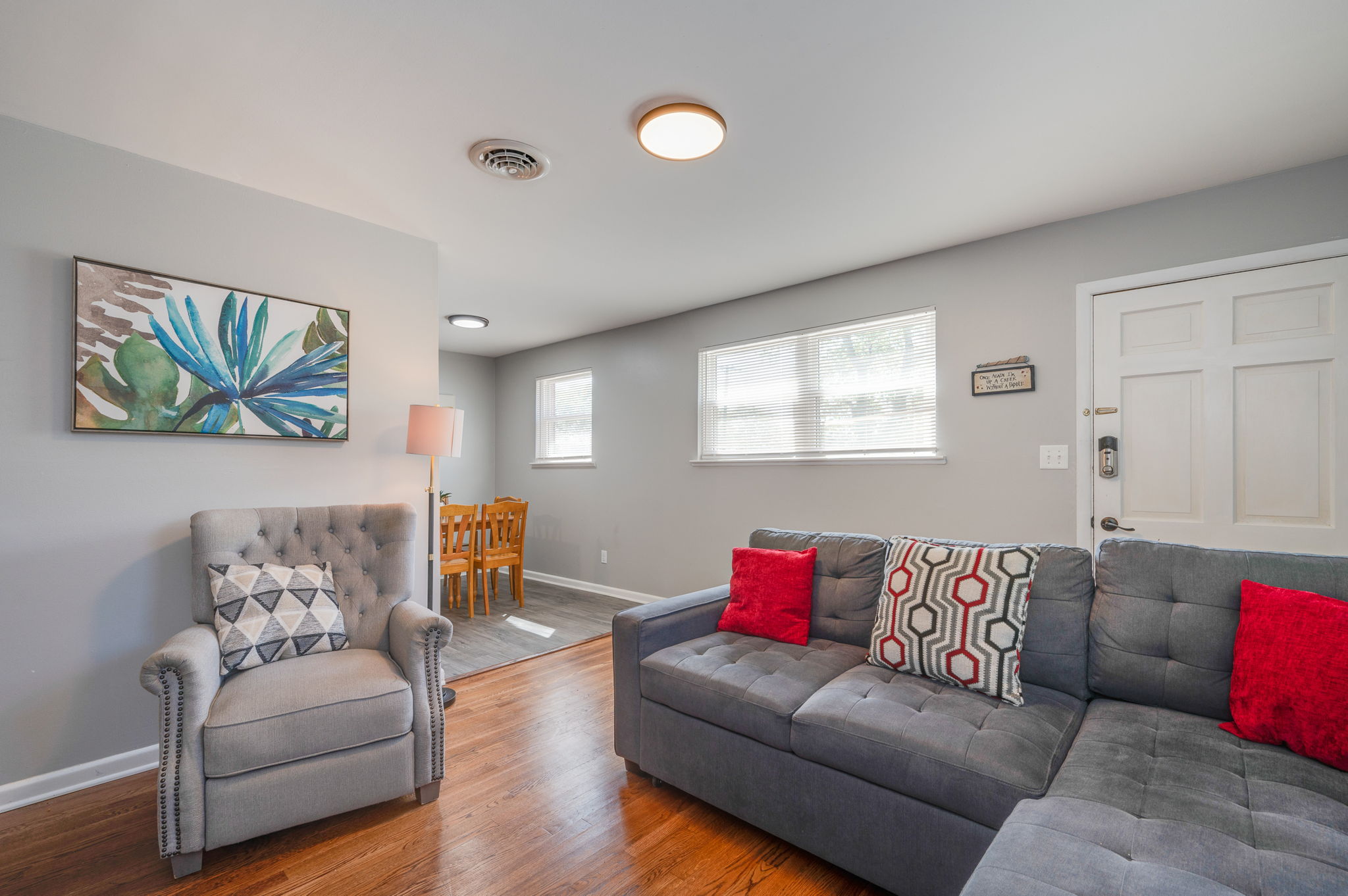 Living room with a modern gray sectional sofa, plush armchair, and decorative artwork.
