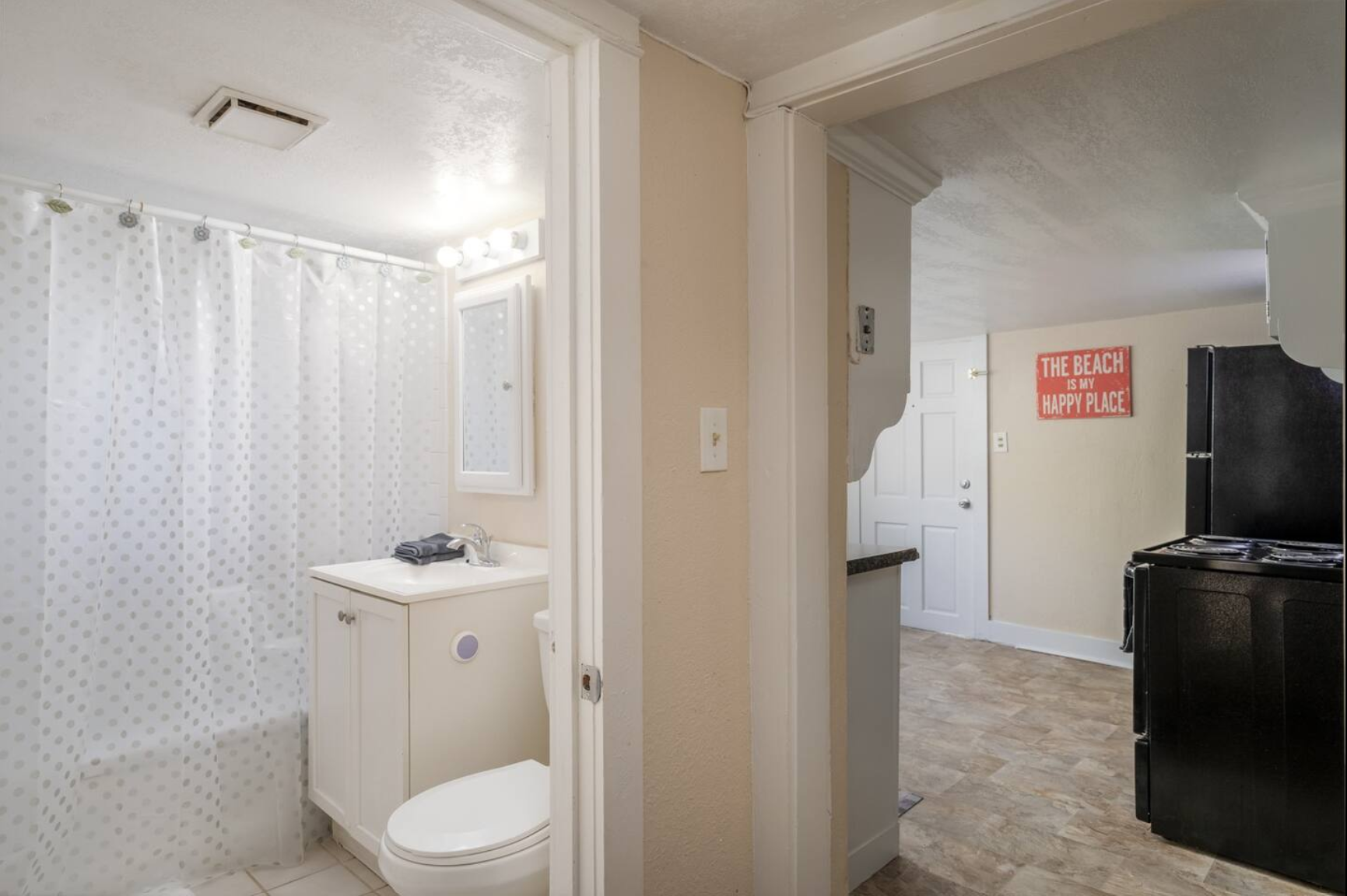 Small bathroom with white vanity, mirror, and shower curtain.