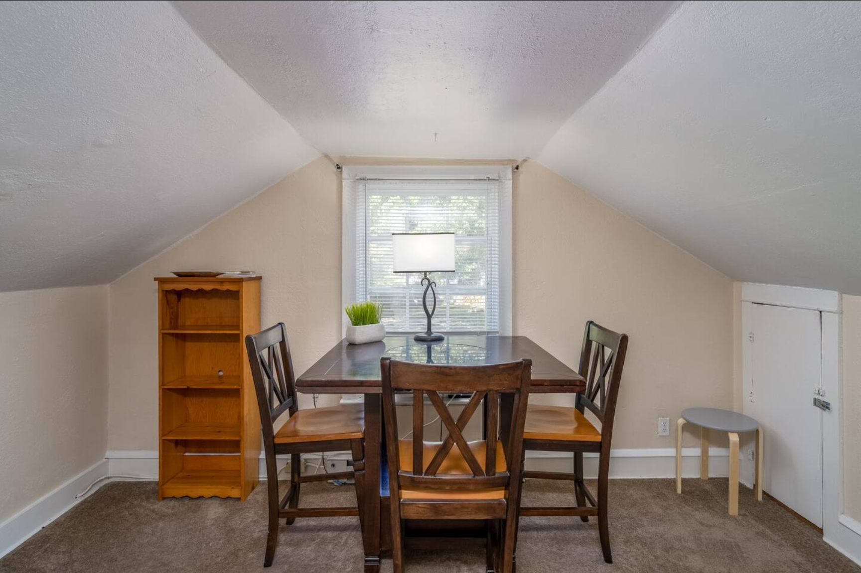 Small dining area with a wooden table and chairs under a sloped ceiling.