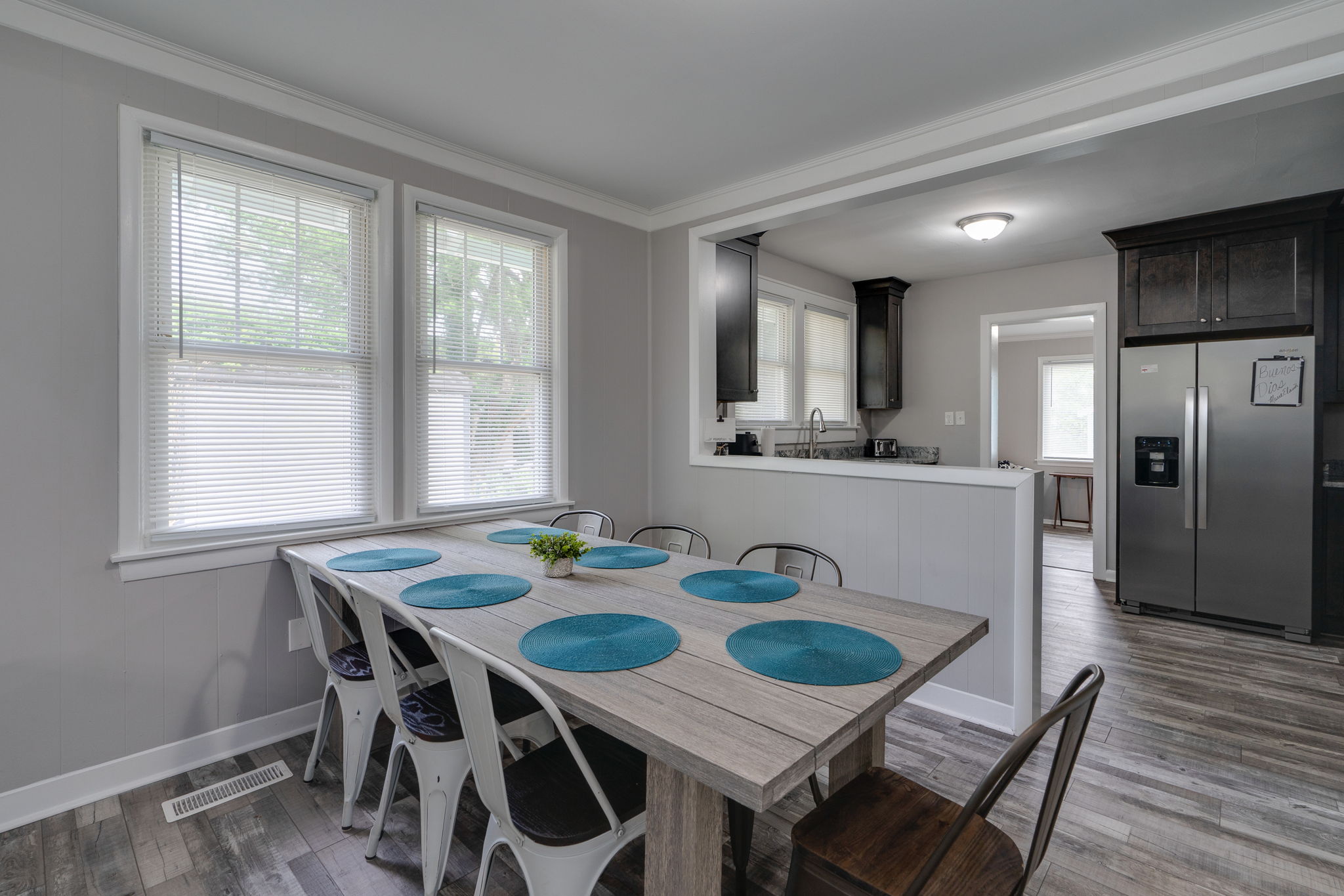 Dining room with a rustic wooden table and metal chairs, connected to the kitchen.