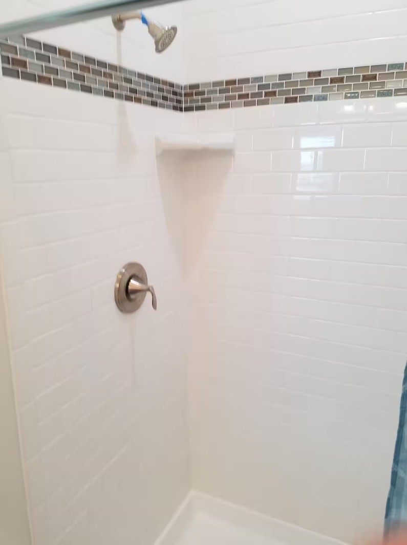 Walk-in shower with white subway tiles and mosaic accent border