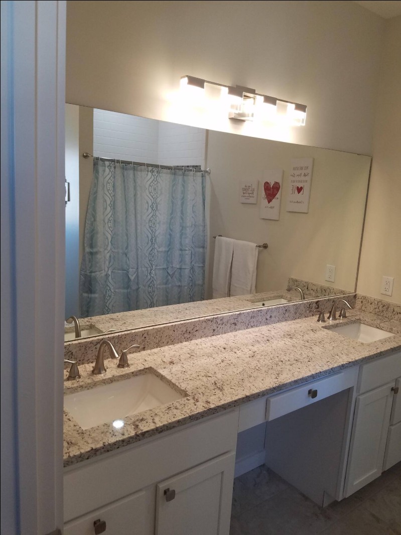 Full view of double sink vanity with granite countertop and mirror