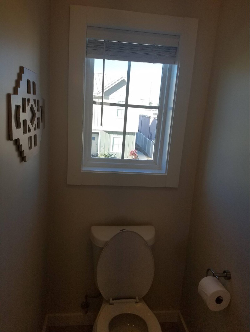 Narrow toilet room with window and geometric wall art