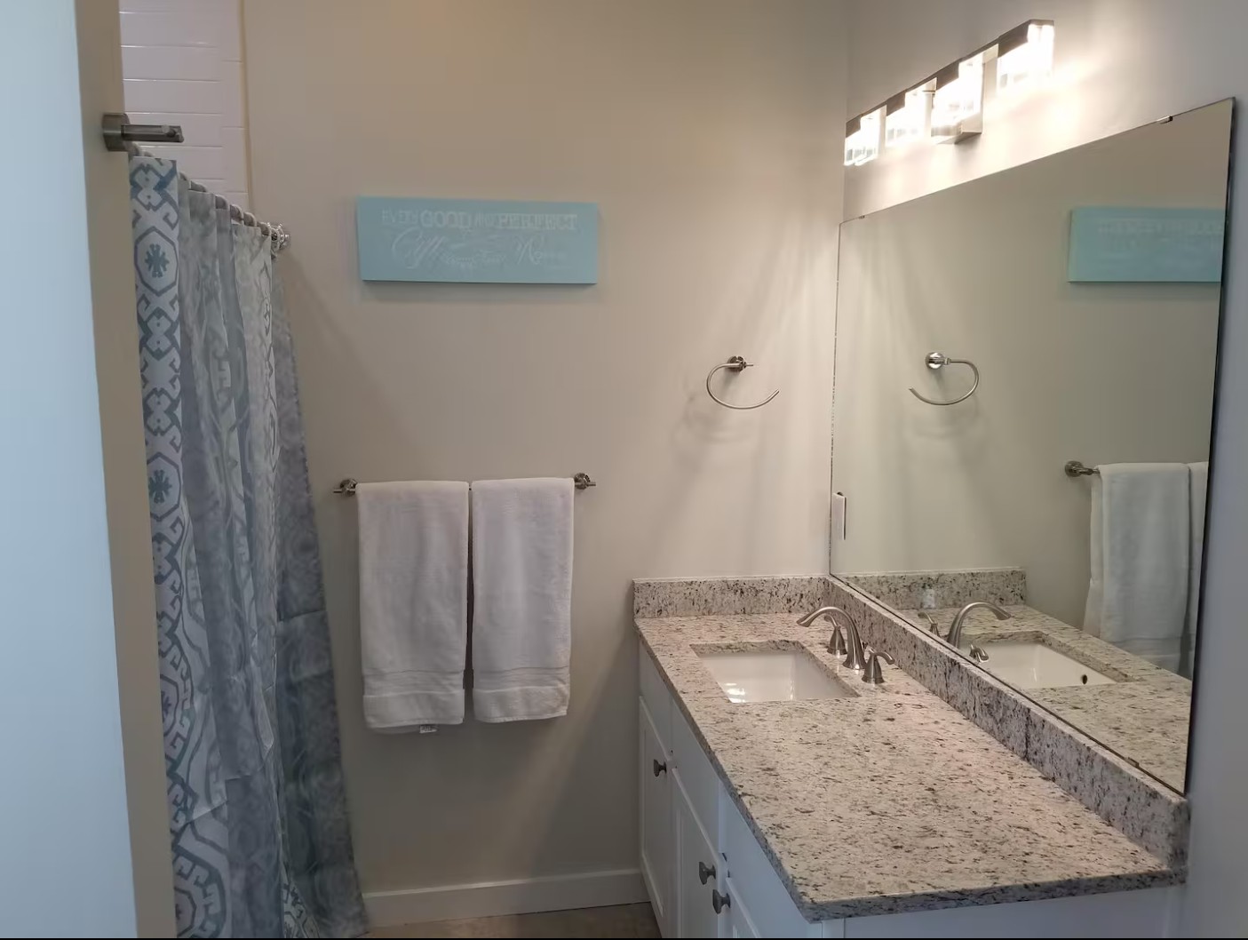 Bathroom with double vanity, mirror, and decorative wall art