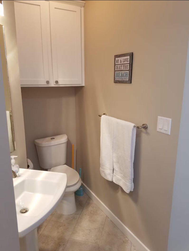 Small bathroom with pedestal sink and towel rack under wall cabinet