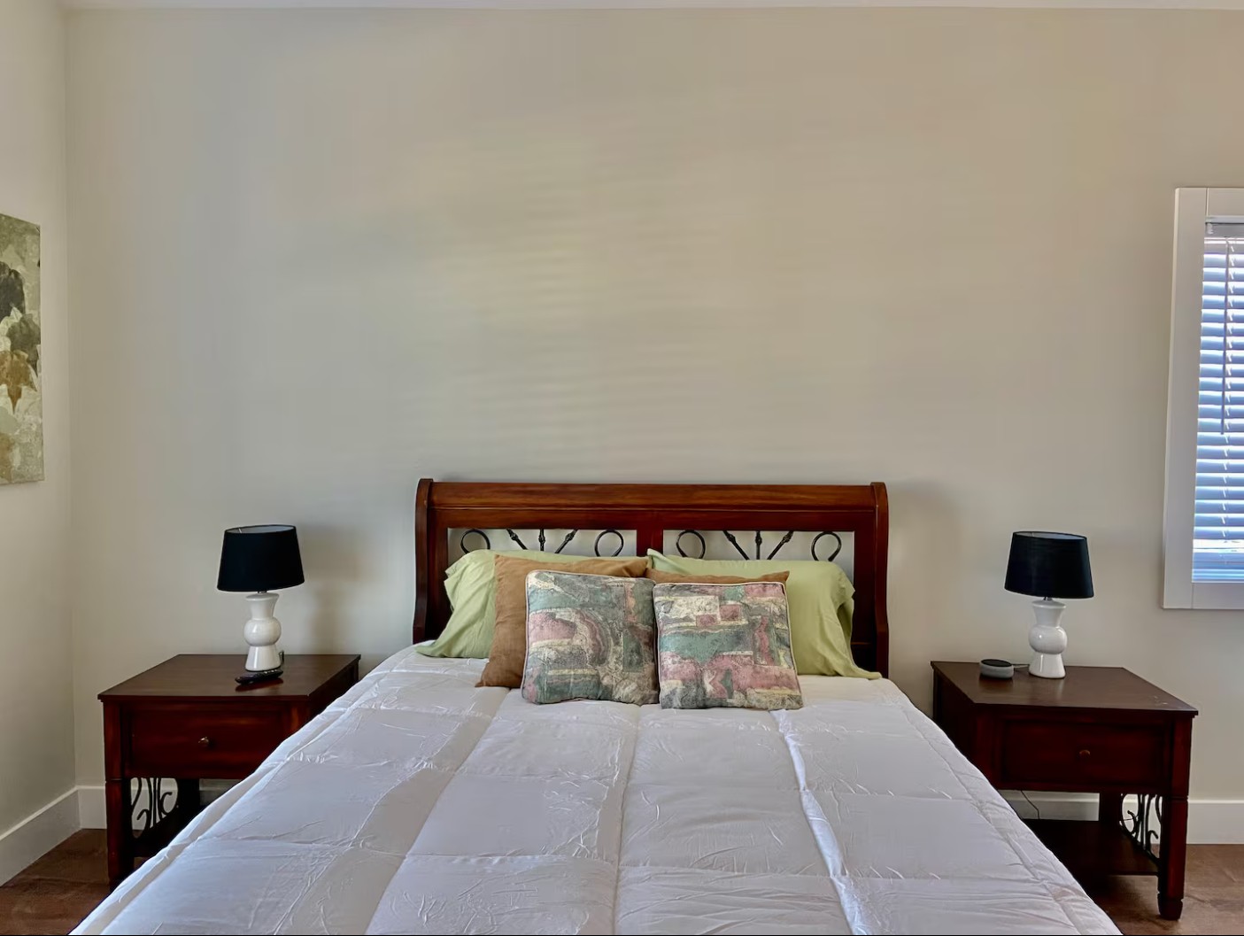 Bedroom with wooden bed frame, nightstands, and neutral bedding