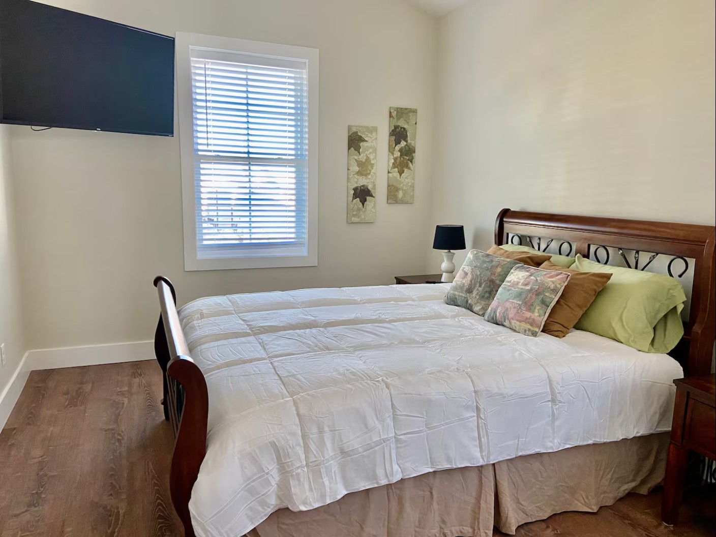 Cozy bedroom with sleigh bed, hardwood floor, and wall-mounted TV