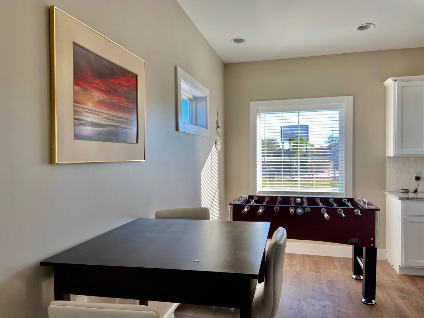 Dining area with black table, white chairs, and foosball table