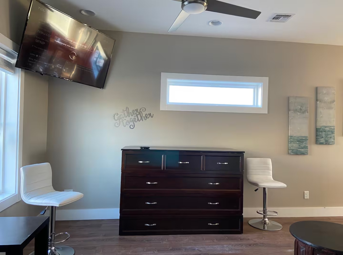 Living room wall with dresser, mounted TV, and modern white chairs