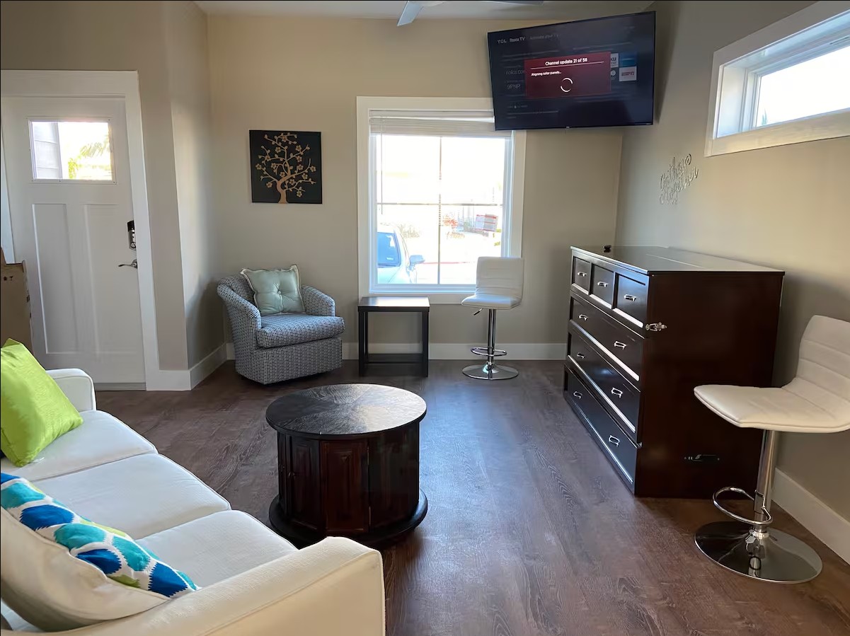 Living room with sofa, armchair, TV, and chest of drawers