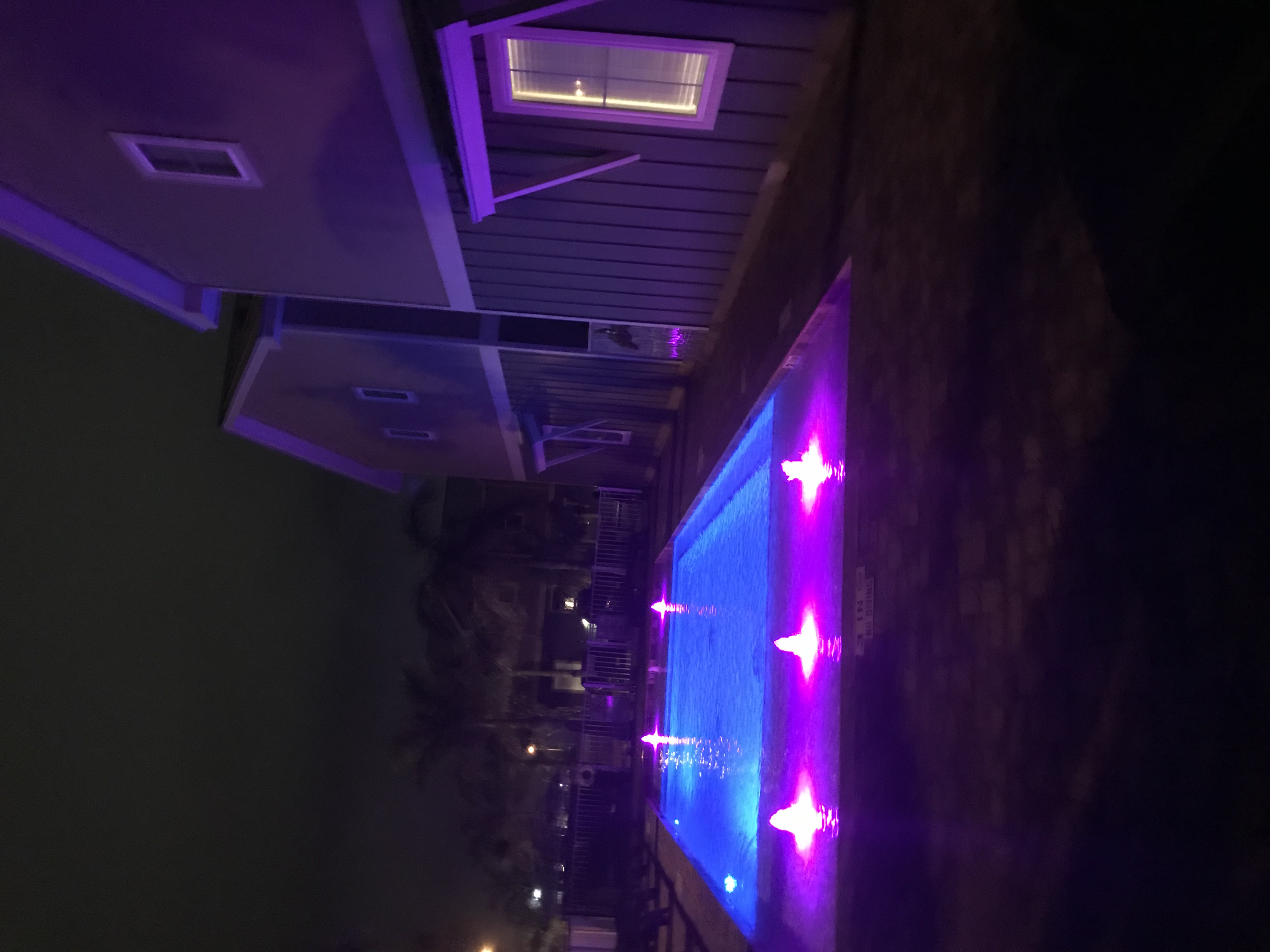 Vacation rental pool lit with purple LED lights at night